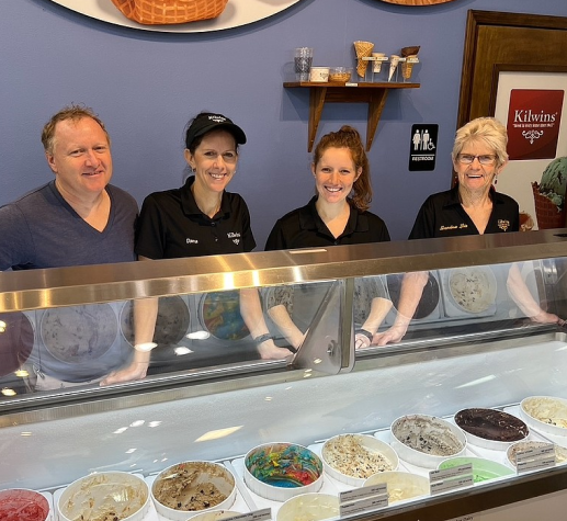 People smiling next to ice cream showcase