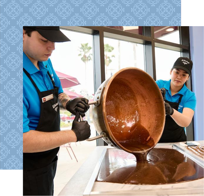 Staff pouring melted chocolate onto a cooling table