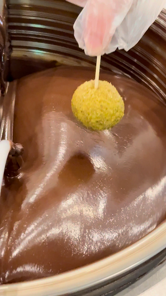 Dipping dubai buckeye in chocolate for coating